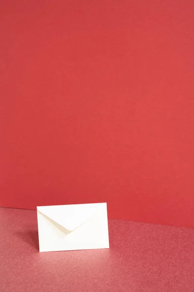 White paper envelope on red table. red wall background