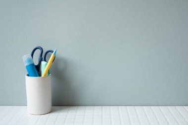 Masaüstü düzenleyici tutkalı, tutkal, kalem, makas beyaz kiremit masasında. gri duvar arkaplanı