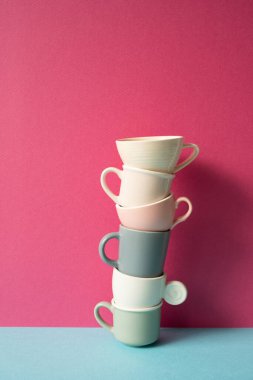 Gökyüzü masasında renkli kahve fincanları yığını. pembe duvar arkaplanı