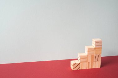 Ahşap merdivenler kırmızı masada. gri duvar arkaplanı. İş geliştirme, büyüme kavramı