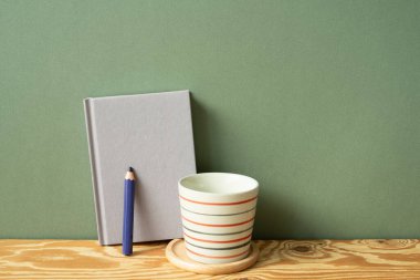 Mor günlük defteri, kalem, tahta masadaki bardak. yeşil duvar arkaplanı