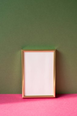 Pembe masanın üzerinde fotokopi alanı olan altın resim çerçevesi. haki yeşil duvar arkaplanı