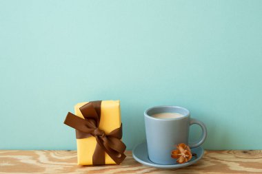 Sarı hediye kutusu ve ahşap masada bir fincan kahve. nane duvarı arkaplanı