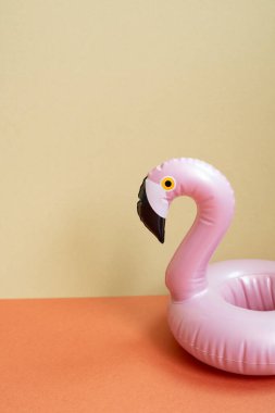 Yaz tatili kavramı. Kırmızı ve bej arkaplanda pembe flamingo şeklindeki yüzme havuzu tüpü.