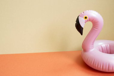 Yaz tatili kavramı. Kırmızı ve bej arkaplanda pembe flamingo şeklindeki yüzme havuzu tüpü.