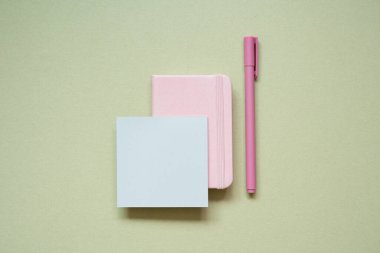 Pembe günlük defteri, not defteri, haki rengi masa arkaplanındaki kalem. en üstteki görünüm