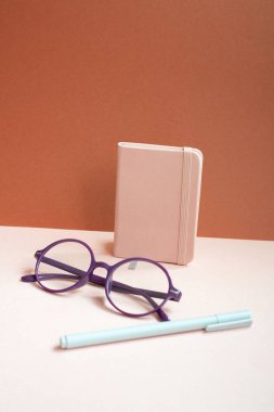 Günlük defteri, kalem, pembe masadaki gözlükler. kırmızı arkaplan