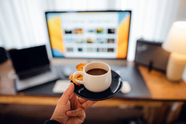 hand holding a cup of coffee at the desk
