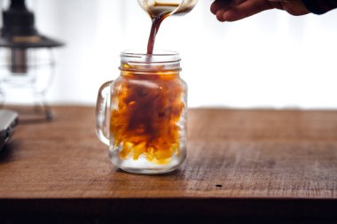 Buzlu kahve masanın üstündeki fincana dökülüyor..