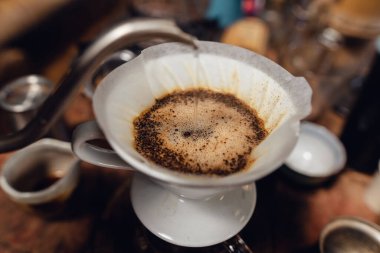 Barista pouring hot water on ground coffee with paper filter to making a drip coffee,Close-up of brewing coffee