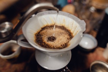 Barista pouring hot water on ground coffee with paper filter to making a drip coffee,Close-up of brewing coffee