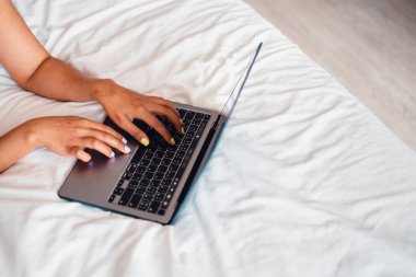 Kafkas kadın dizüstü bilgisayar kullanarak yatakta yatıyor, dizüstü bilgisayar boş yatakta.