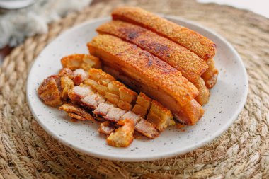 Beyaz tabakta kızarmış domuz göbeği.