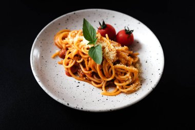 Siyah arka planda domates soslu ve peynirli spagetti.