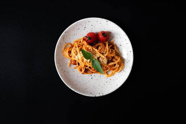 Spaghetti with tomato sauce and cheese on black background