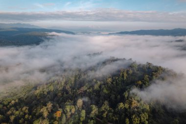 Güneşin doğuşunu ya da günbatımını dağların üzerinde ve sisli.
