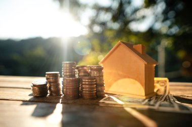 Yığınla para ve ev tasarrufları ahşap masaya, doğal arka plan ışığı