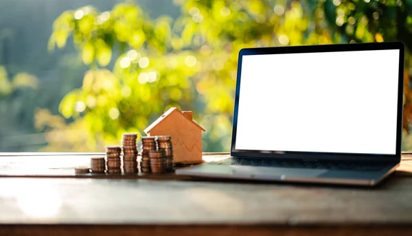 Laptop and money placed on a wooden table, cool light natural background.