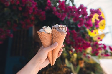 Adam elinde çiçek arkaplanlı dondurma tutuyor.