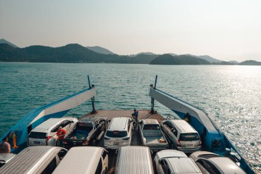 İnsanlar ve arabalar adaya giden teknelerde