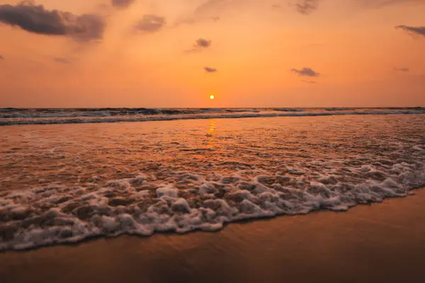 Sunset on the beach and ocean waves and orange sky