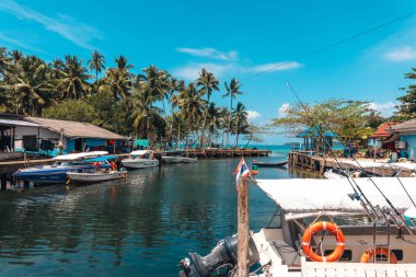 Sakin bir limanda sallanan kayıklar, köpüklü suya yansıyor.