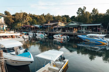 Beyaz yatlar ve balıkçı tekneleri hoş bir ada liman kasabasında hafifçe sallanır.