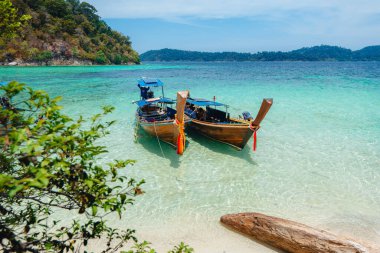 Adadaki temiz sahilde tahta bir tekne.