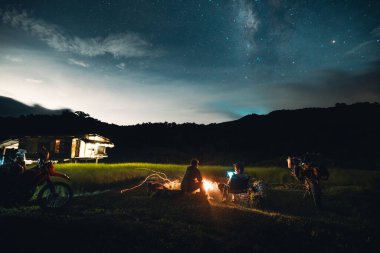Geceleri kamp ateşi yıldızlarla ve gökyüzünde Samanyolu 'yla pirinç tarlasının ortasında kamp ateşi.