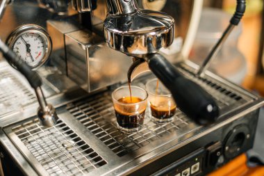 Kahve makinesinin kahvesi, kahve makinesinin bardağına dökülüyor.