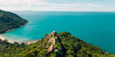 Koh Phangan, Tayland 'da, büyük bir kayanın tepesinde duran gezgin, sakin bir körfeze bakıyor.