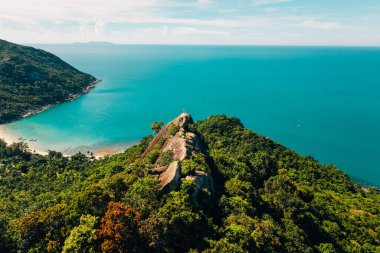 Koh Phangan, Tayland 'da, büyük bir kayanın tepesinde duran gezgin, sakin bir körfeze bakıyor.