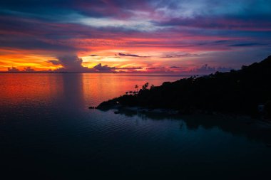 Okyanus üzerinde gün batımı, derin turuncu ve mor renkler döküm su ve gökyüzü üzerinde.