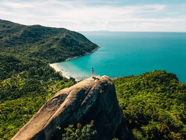 Koh Phangan, Tayland 'da, büyük bir kayanın tepesinde duran gezgin, sakin bir körfeze bakıyor.