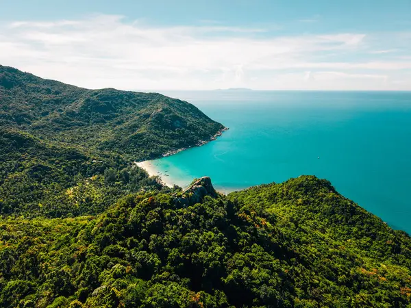 Koh Phangan, Tayland 'da, büyük bir kayanın tepesinde duran gezgin, sakin bir körfeze bakıyor.
