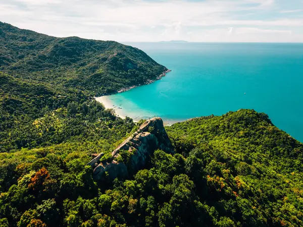 Koh Phangan, Tayland 'da, büyük bir kayanın tepesinde duran gezgin, sakin bir körfeze bakıyor.