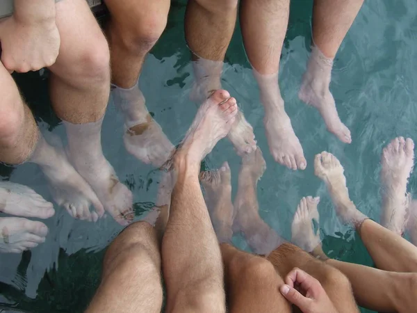 Feet of tourist resting on tropical resort. Legs of men in water of sea. Lifestyle concept. Enjoying summer vacations. People on holidays in tropics. People put their feet in the water