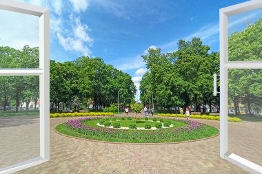 Çiçekli yataklar ve çiçeklerle şehir parkına açılan pencereyi aç. Şehir parkındaki çiçek tarhı manzarası. Kasabaya bahar geldi. Şehir manzaralı bir oda penceresi. Çiçekli laleleri olan bir asma.