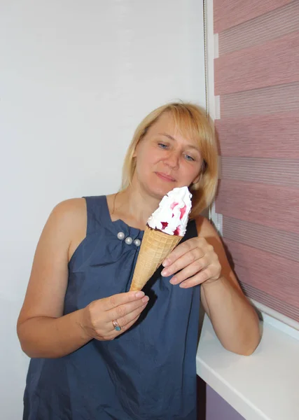 modern woman is about to eat ice cream. Beautiful woman eating ice cream. Woman smiling and eating dessert. Blonde woman holding ice cream in hands