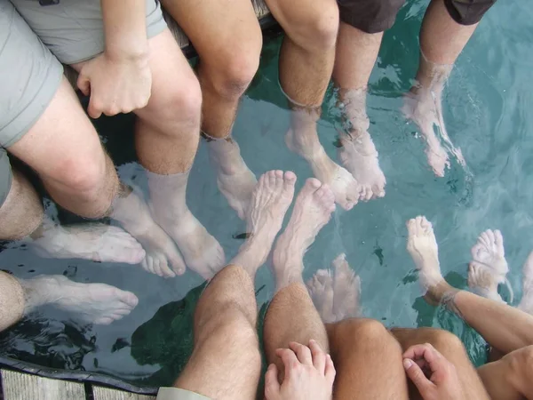 Feet of tourist resting on tropical resort. Legs of men in water of sea. Lifestyle concept. Enjoying summer vacations. People on holidays in tropics. People put their feet in the water