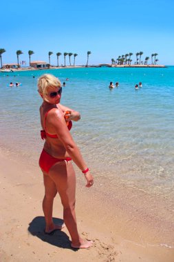 Genç kadın egzotik tatil sırasında koruyucu krem sürülür. Güneş banyosu sırasında krem kullanan sarışın kadın. Omuz için çekici kadın sağlıklı cilt güneş koruyucu uygulanıyor. Cilt Bakımı