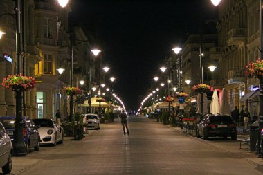 Lodz - Polonya. 17 Ağustos 2019: Lodz Piotrkowska 'nın merkez caddesi. Geceleri Polonya 'nın ana turistik caddesi Lodz Piotrkowska. Piotrkowska caddesindeki Lodz 'da insanlar dinleniyor. Kafede insanlar rahatlar.