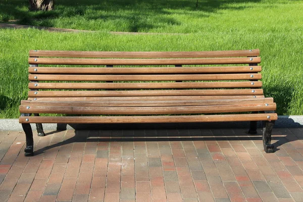 公园里的木制长椅 公园里漂亮的长椅 空荡荡的长椅在绿草的美丽公园里 有地方休息的夏季公园 图库照片