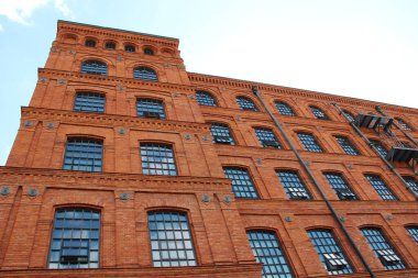 Lodz - Polonya. 17 Ağustos 2019: Eski tuğla bina cephesi. Polonya 'nın Lodz şehrinde pencereleri olan eski bir fabrika binası. Polonya 'da eski mimari. Kırmızı tuğla fabrikası cephesi