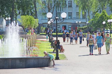 Chernihiv - Ukrayna. 19 Temmuz 2018: Şehir çeşmelerinde suya yürüyerek dokunmaya çalışan küçük bir kız. İnsanlar şehir parkında fıskiyeli dinleniyor. Güneşli bir yaz günü. Çocuk şehir çeşmesinin suyuyla oynuyor. Yaşam tarzı kavramı
