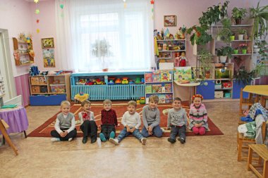 Chernihiv - Ukrayna - 08 Eylül 2019 Anaokulunda halının üzerinde oturan çocuklar. Mutlu çocuklar. Bebek gülümsüyor. Mutlu bir çocukluk. Çocuklar anaokulunda gülüyorlar. Komik çocuklar. Gülümseyen çocuklar grubu