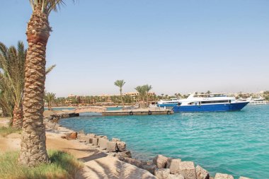 Hurghada - Mısır. 30 Temmuz 2018: Hurghada körfezine demirlemiş gemi ve yatlar. Kıyıya yakın duran gemiler. Boyalı modern gemi kıyıya yakın denizde duruyor. Çayırı olan deniz kenarı tatil beldesi.