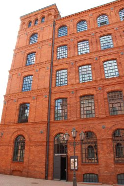 Eski tuğla bina cephesi. Polonya 'nın Lodz şehrinde pencereleri olan eski bir fabrika binası. Polonya 'da eski mimari. Kırmızı tuğla fabrikası cephesi