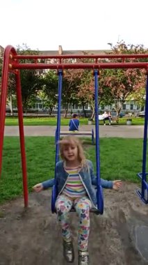 Küçük kız salıncakta sallanıyor. Çocukluk daha iyi yıllar. Mutlu çocuk. Şehir parkında küçük bir kız salıncakta sallanıyor. Çocuk dışarıda vakit geçiriyor. Çocuk parkında vakit geçiriyor