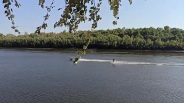 Chernihiv - Ukrayna. 17 Haziran 2024: Wakeboardcu suyun üzerinde yükseğe zıplıyor. Ekstrem sporlardan zevk almak. Sporcu hareketinden memnun. Gölde mayo giymiş genç bir adam. Su sporları
